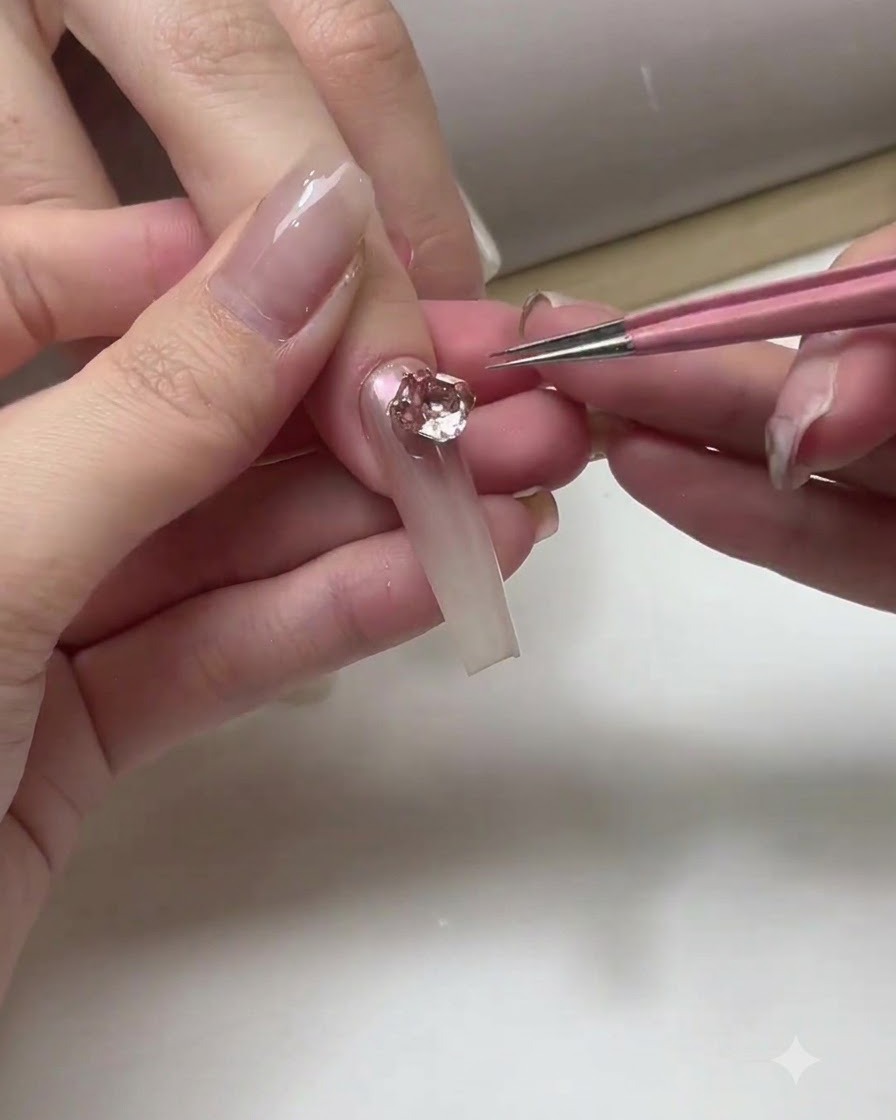 Eine Nageldesignerin trägt eine Schicht klaren Top Coat auf die Oberfläche der fertiggestellten Ombré-Nägel auf.