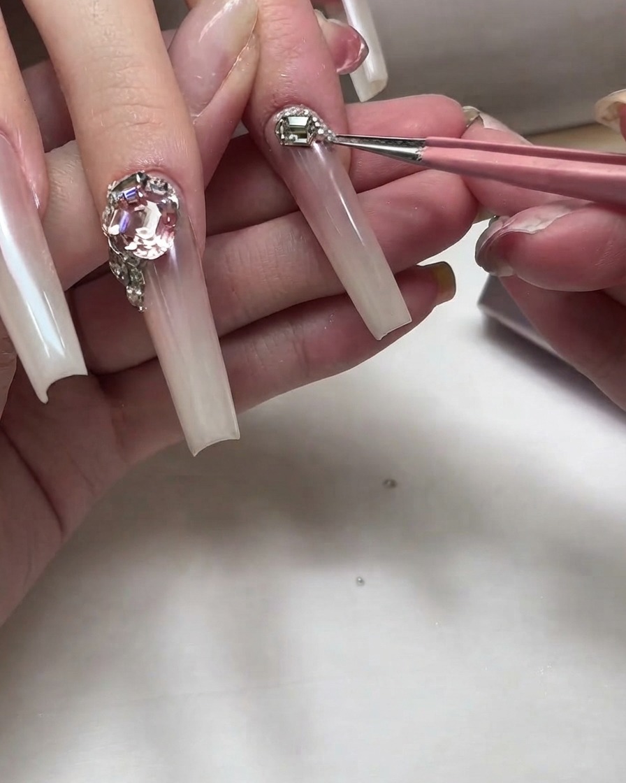 Präzisionspinzetten platzieren kleine silberne Metallnieten und Micro-Strasssteine nahe am Nagelband.