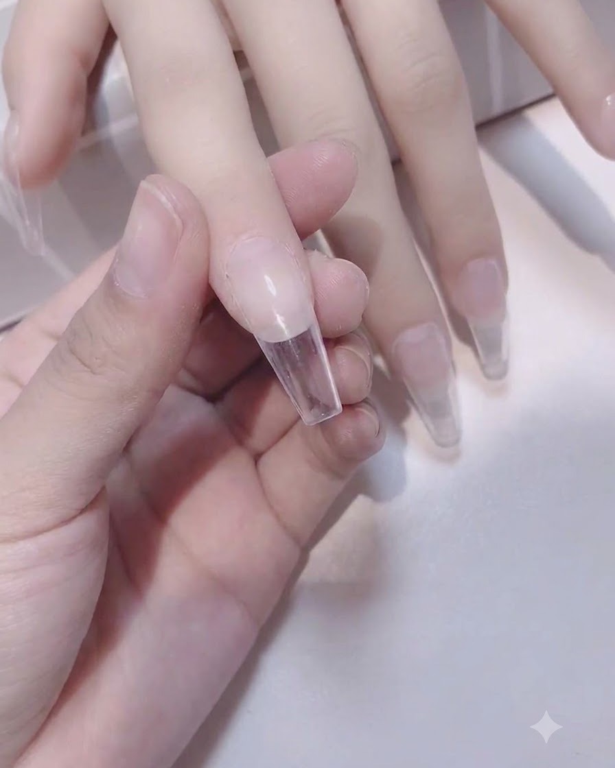 Ein Schwammpinsel trägt eine zweite Schicht weißes Gel auf die Nagelspitze auf.