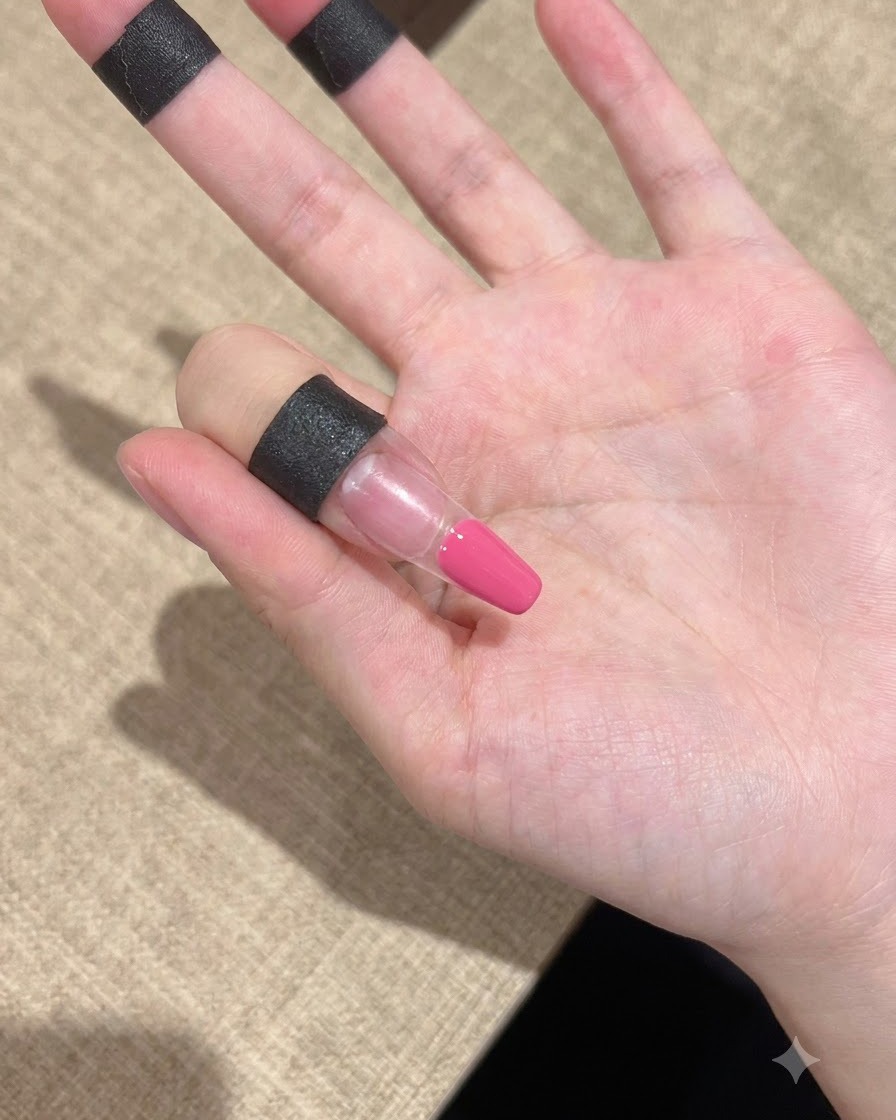 Eine Nahaufnahme eines Fingers mit säuberlich auf den Spitzenbereich aufgetragenem rosa Gel.