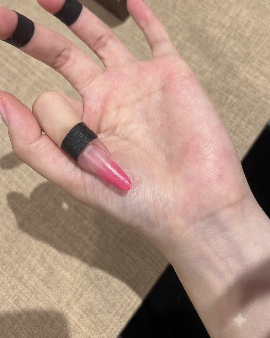 Eine Hand positioniert unter einer kompakten UV-Lampe zum Aushärten der rosa Gradient-Nägel.