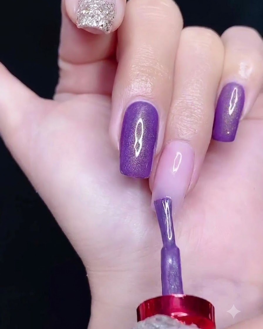 Ein Pinsel trägt lila Gel-Nagellack auf den oberen Bereich eines Nagels auf.