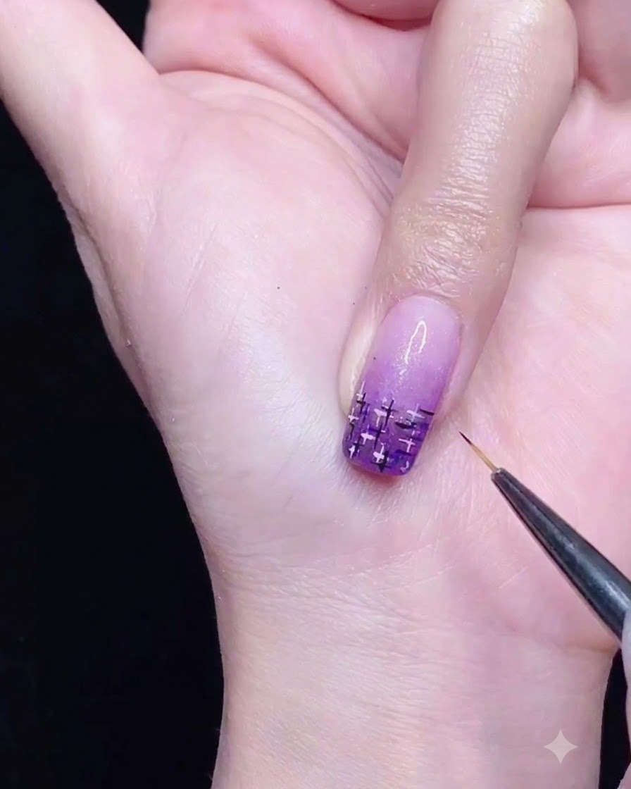 Ein Fine-Liner-Pinsel zeichnet sich kreuzende schwarze und silberne Linien auf einen lila Farbverlaufsnagel.