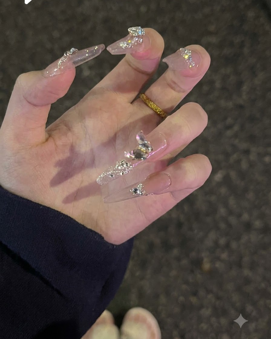 Eine nach oben gedrehte Hand, um Oberflächen-Glitter und glitzernde Diamantkristalle auf Nude-Nägeln zu zeigen.