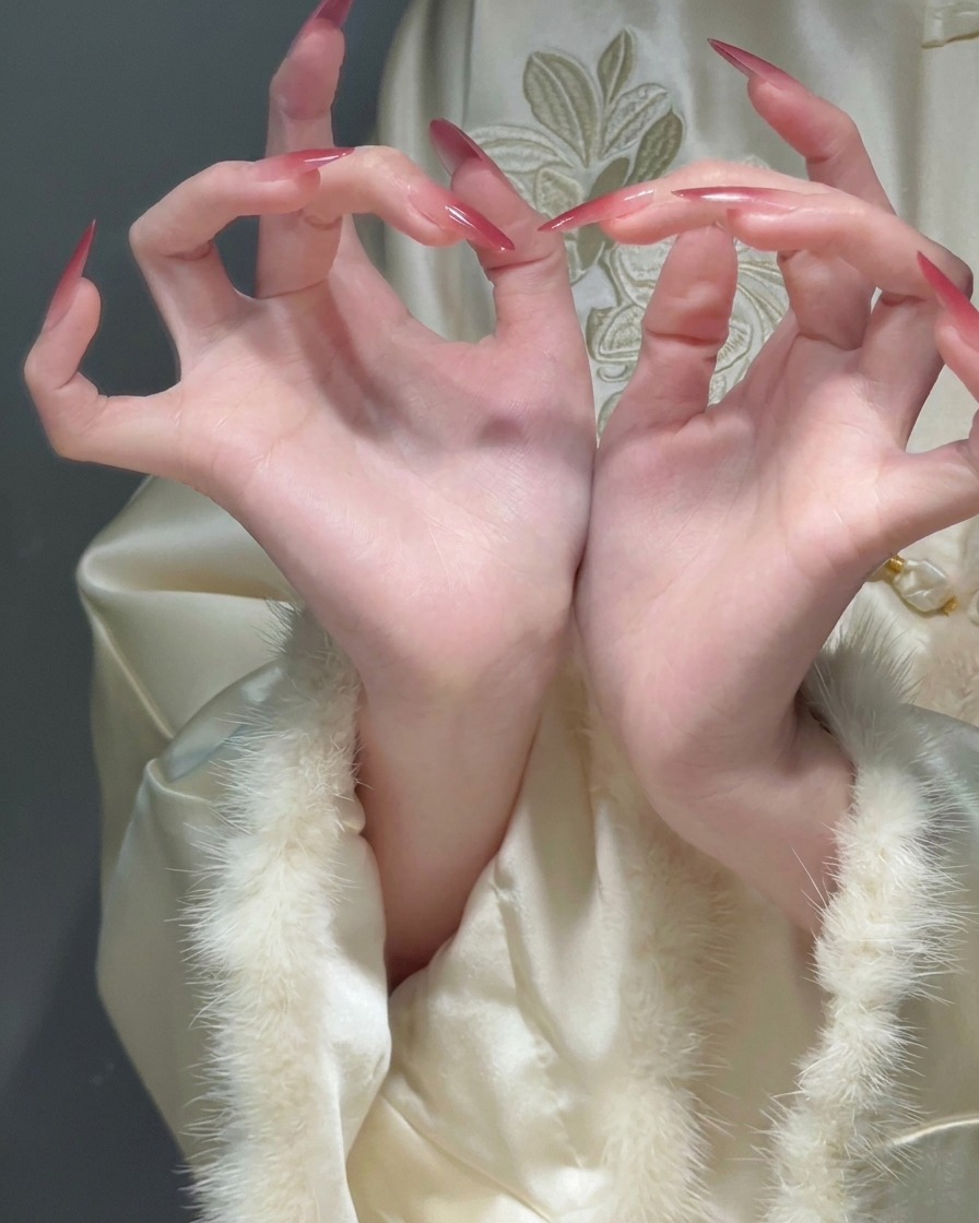 Nahaufnahme gewölbter Finger mit langen Stiletto-Nägeln und einem weichen Übergang von einer transparenten Basis zu roten Spitzen.