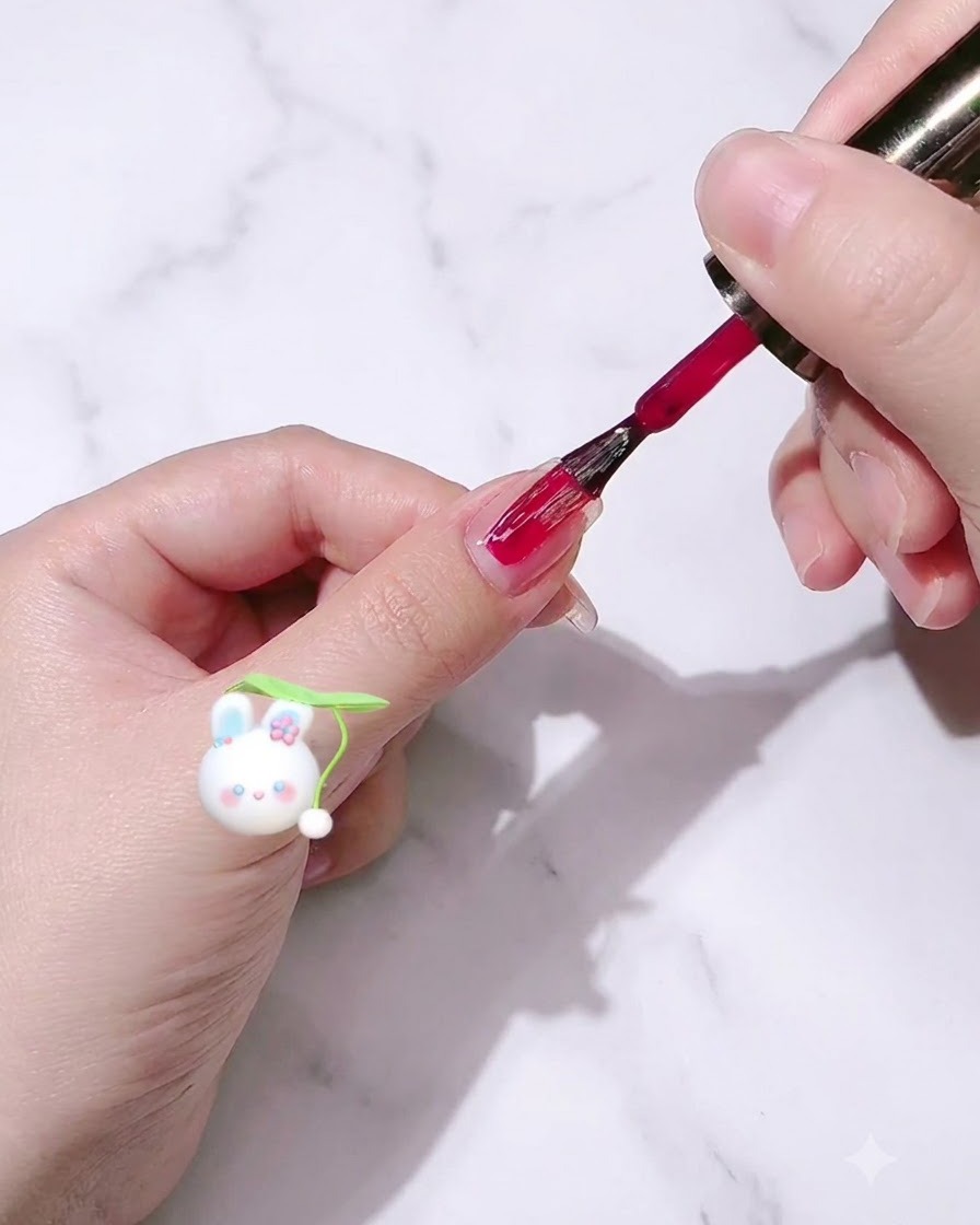 Ein Nagellackpinsel trägt rosenroten Gel-Lack auf einen Fingernagel auf.
