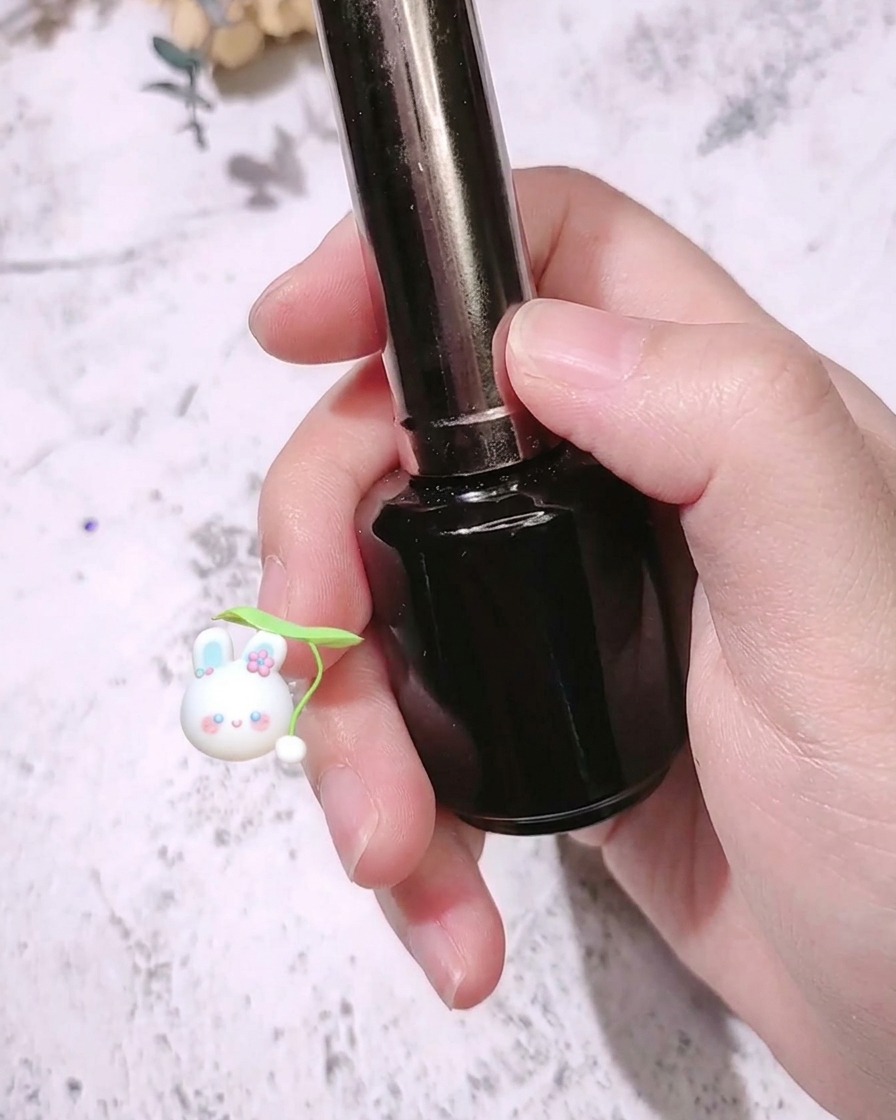 Ein Nagelpinsel trägt einen matten Überzugslack über einem leuchtend rosenroten Fingernagel auf.