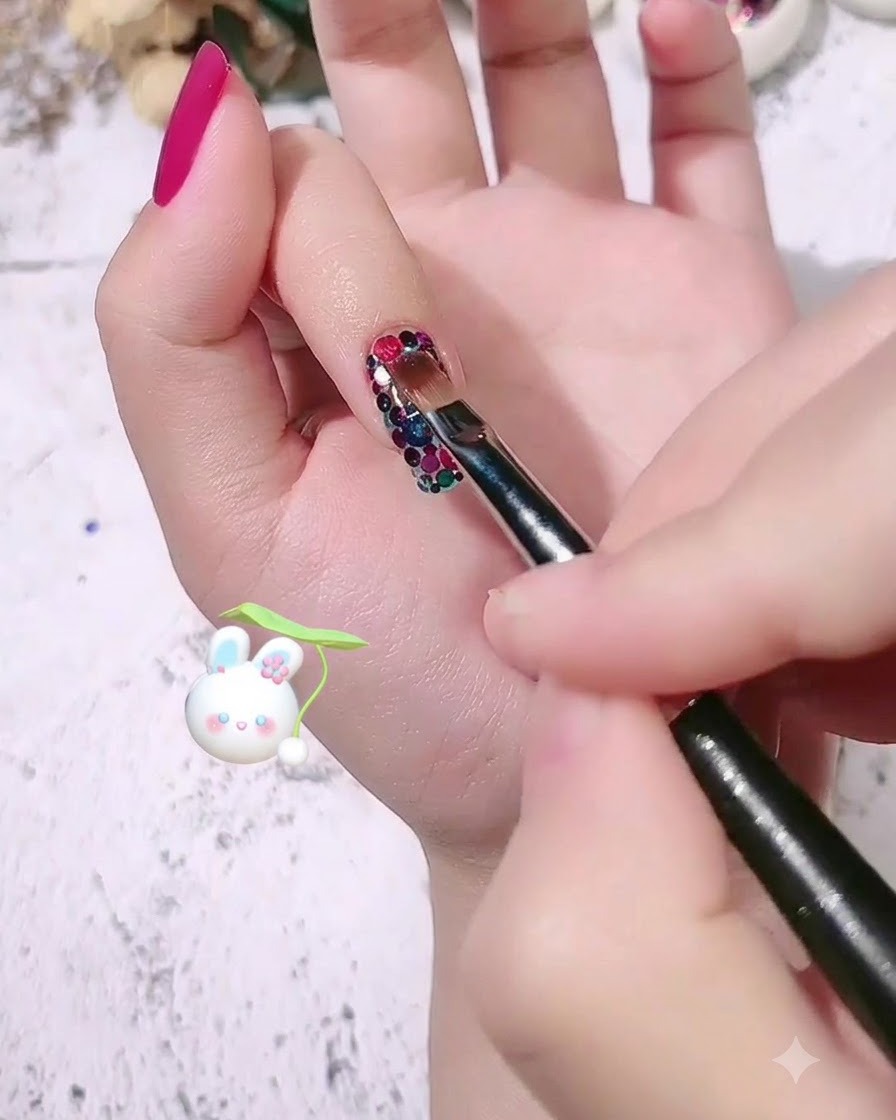 Ein Nagelpinsel trägt eine klare Schicht Modelliergel über dem gemusterten Pailletten-Nageldesign auf.