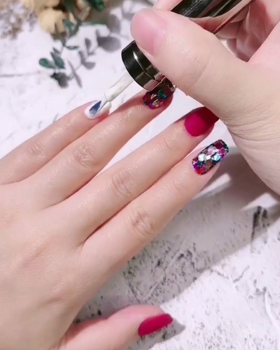 Ein Nagelpinsel trägt milchweißen Gel-Lack auf den Nagel eines kleinen Fingers auf.