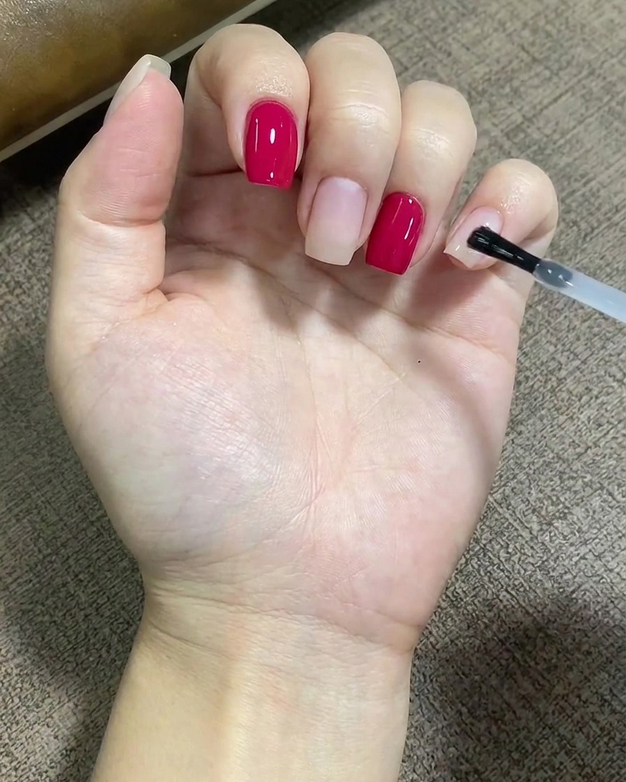 Ein Pinsel trägt eine klare Schicht Unterlack gleichmäßig über die Oberfläche eines Fingernagels auf.