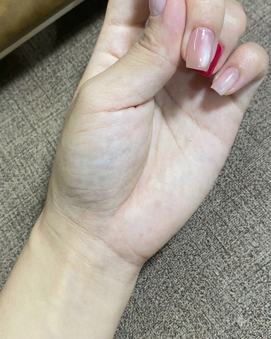 Eine Nahaufnahme einer Hand beim Ausruhen, während eine tragbare UV-LED-Lampe den Gel-Nagellack auf den Nägeln aushärtet.