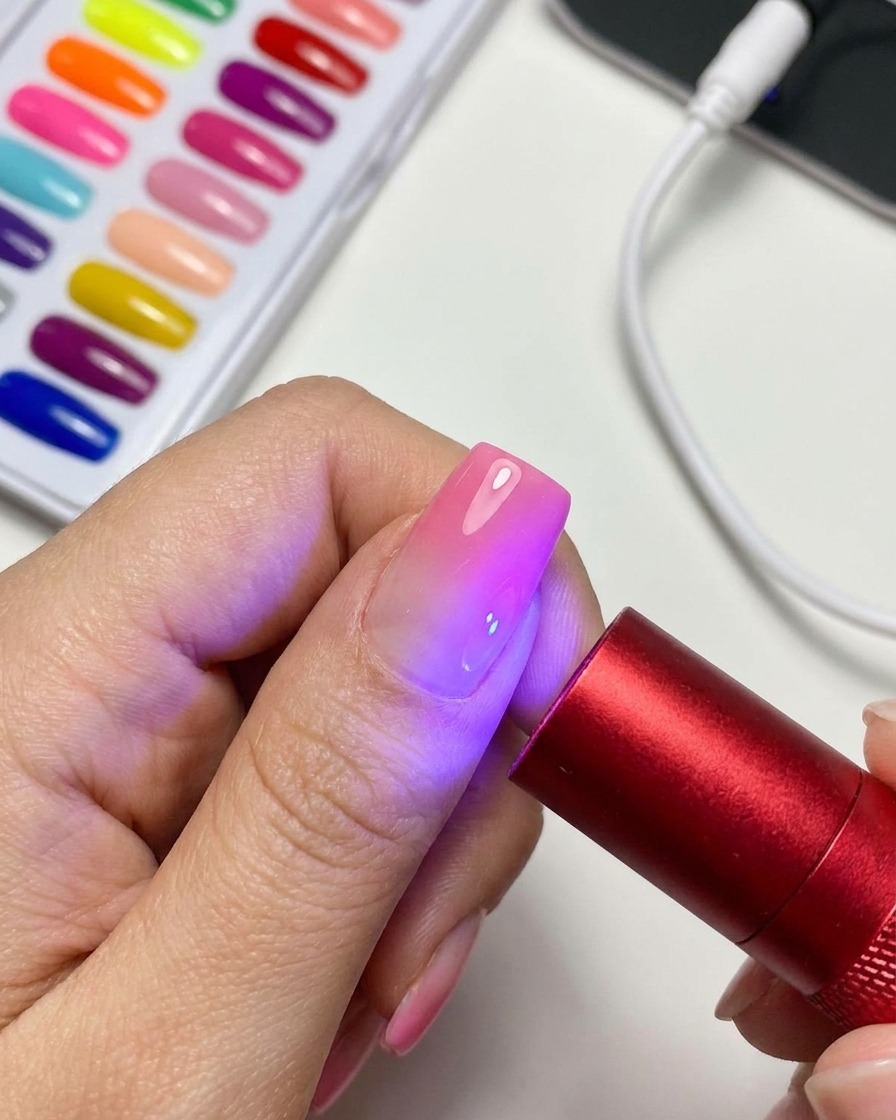 Eine tragbare rote UV-/LED-Lampe beleuchtet einen fertigen magnetischen Cat-Eye-Gel-Nagel.