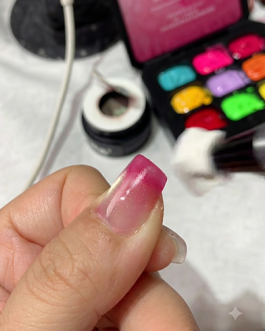 Ein Schwammapplikator tupft magenta-rotes Gel-Polish auf die Spitze eines Fingernagels, um einen Farbverlauf aufzubauen.