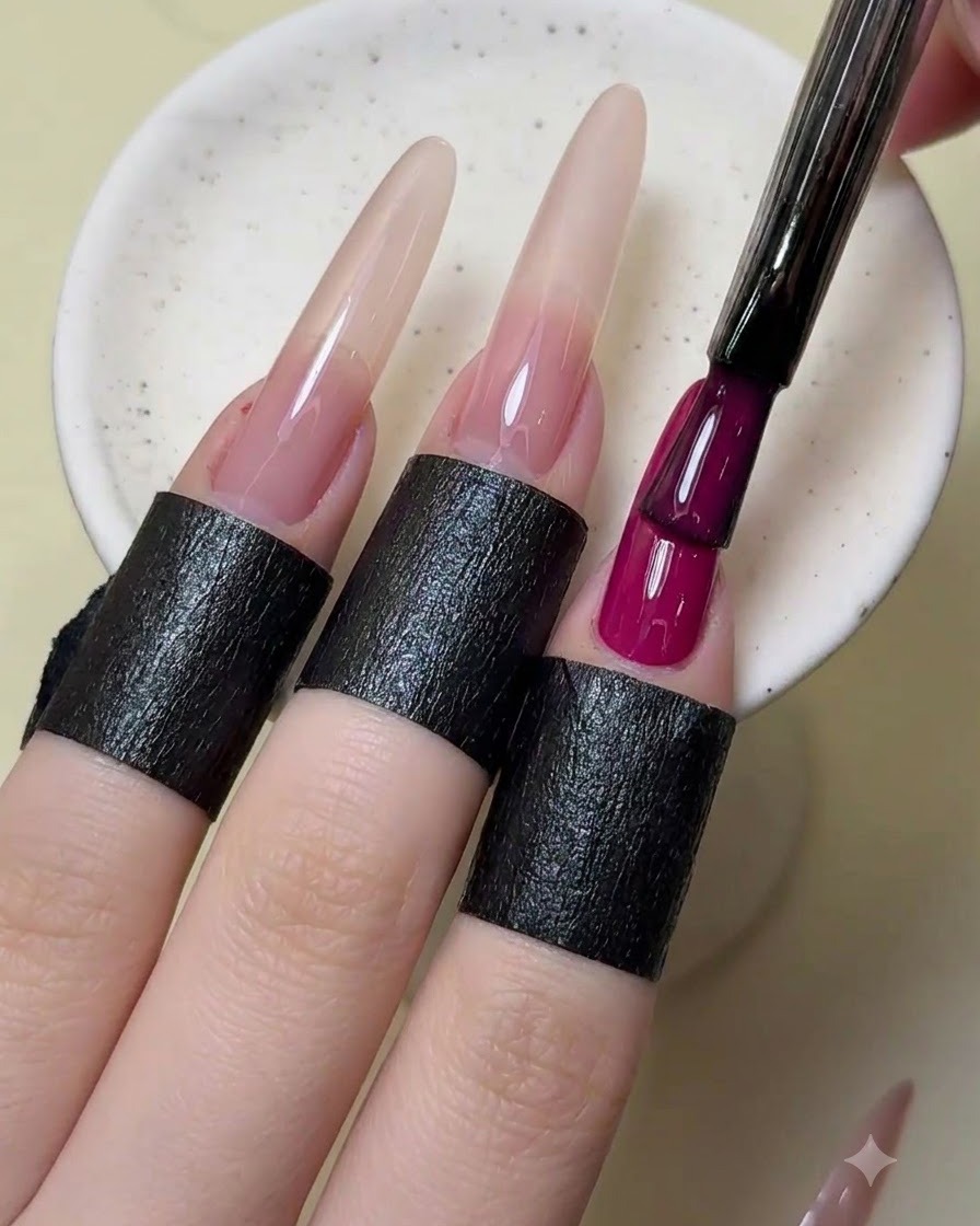 Ein Nagelpinsel fügt dem Zeigefinger eine zweite Schicht opaken magentaroten Lack hinzu.