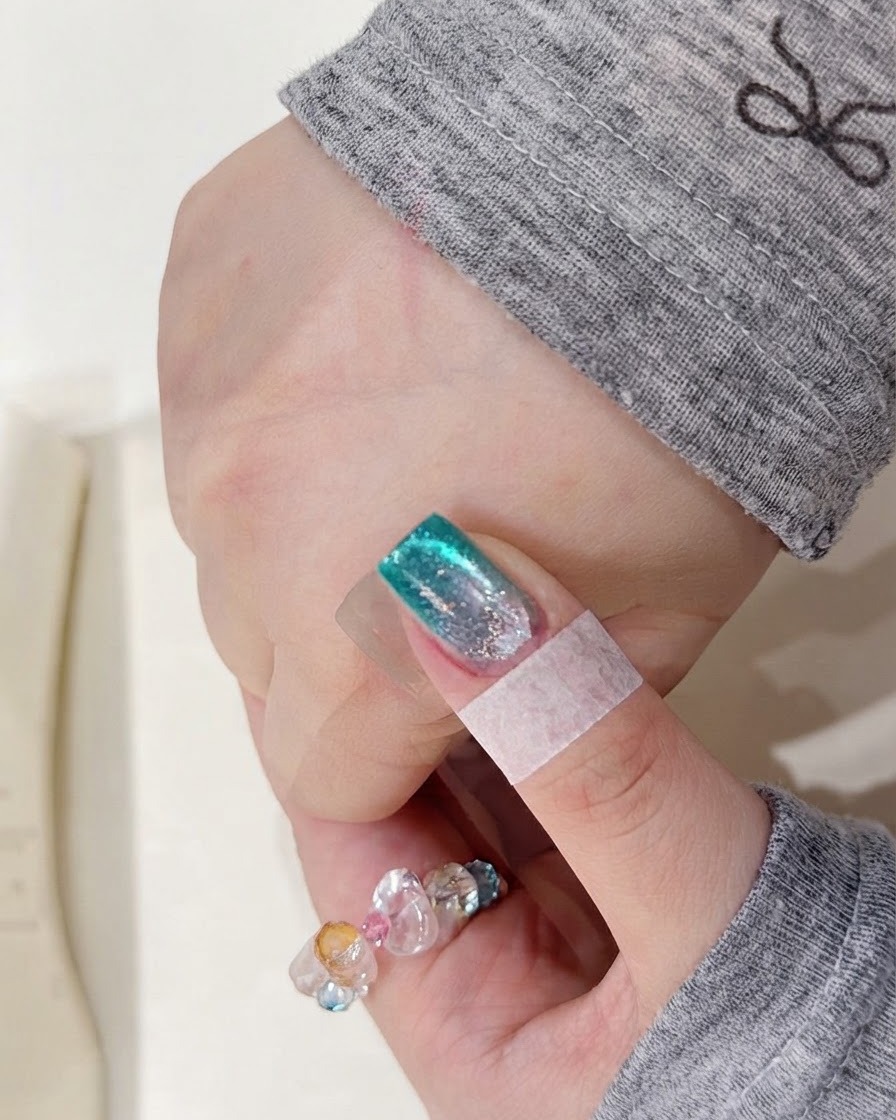 Eine Hand liegt in einer UV-Nagellampe, um die frisch aufgetragene Aquarell-Pigmentschicht auszuhärten.
