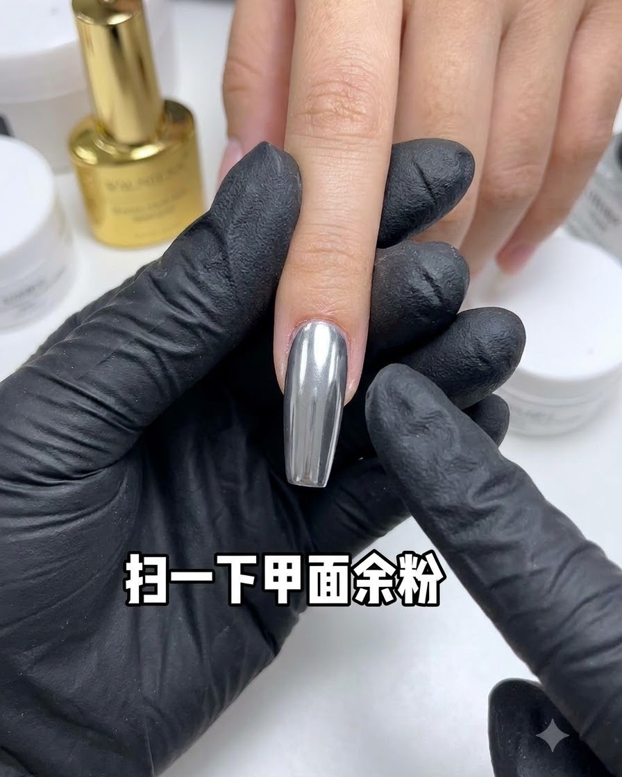 Ein Staubpinsel fegt überschüssiges Pulver von einem reflektierenden Chrom-Nagel weg.