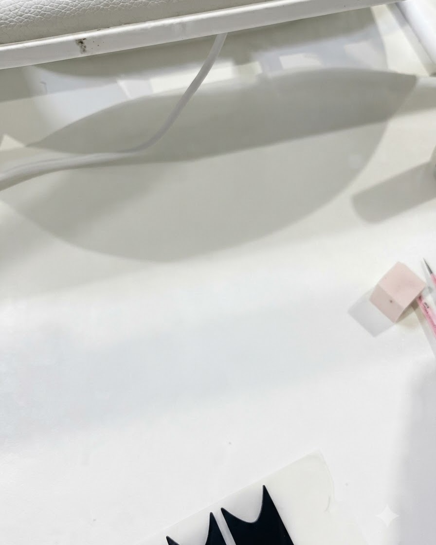 Arbeitsplatzansicht mit Anwendungsverbrauchsstoffen, während der Topcoat für die Nagelstruktur vorbereitet wird.