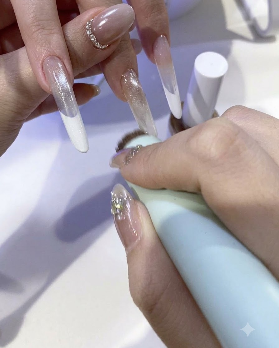 Ein Pinsel trägt eine glitzernde Fairy-Powder-Gel-Mischung auf die Spitze eines verlängerten Nagels auf.