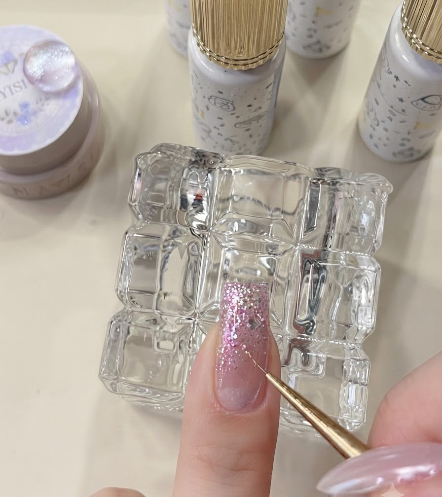 Ein Detailwerkzeug platziert Sternenflocken auf einem ungehärteten Glitter-Nagel.