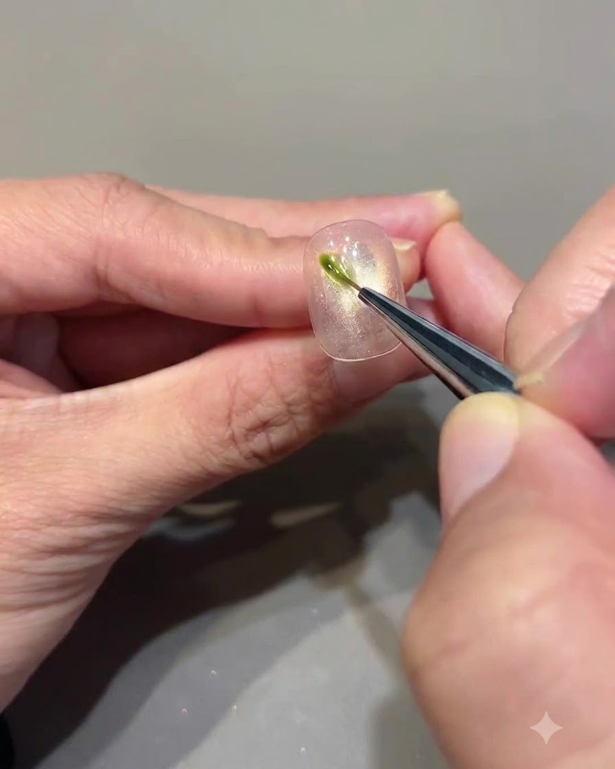 Ein Fine-Liner-Pinsel trägt einen kurzen vertikalen Strich aus avocadogrünem Gel auf einen Cat-Eye-Nagel auf.