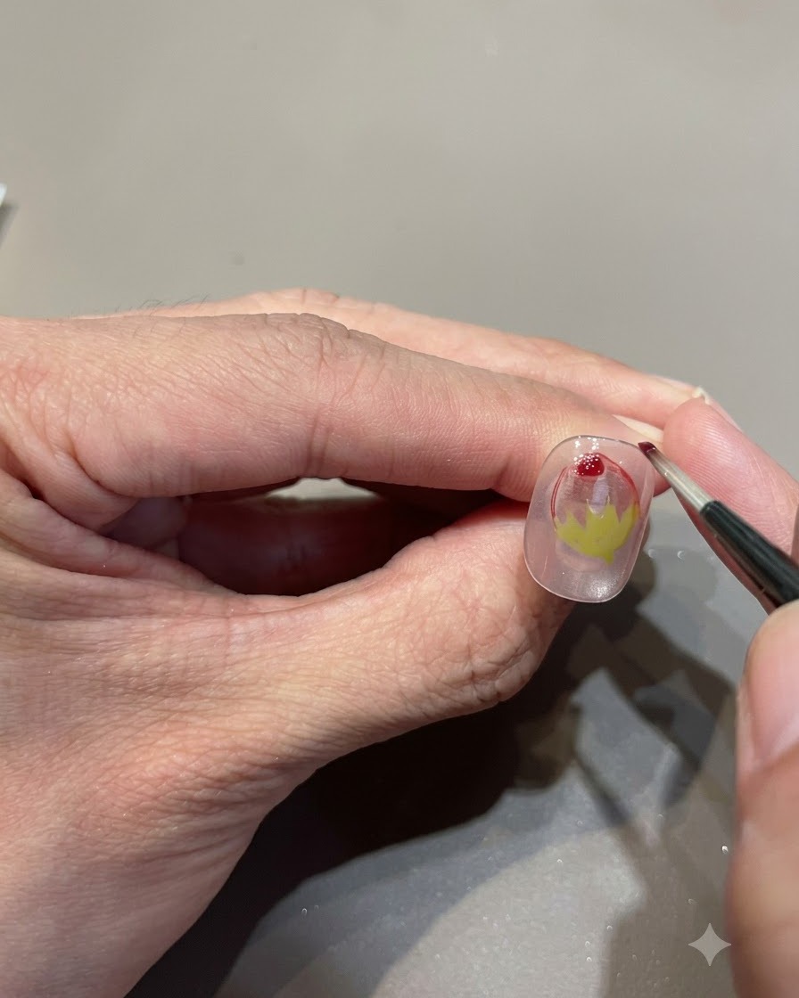 Nahaufnahme eines feinen Pinsels, der einen Tropfen rotes Glasgel hinzufügt, um den Erdbeer-Farbverlauf zu verstärken.
