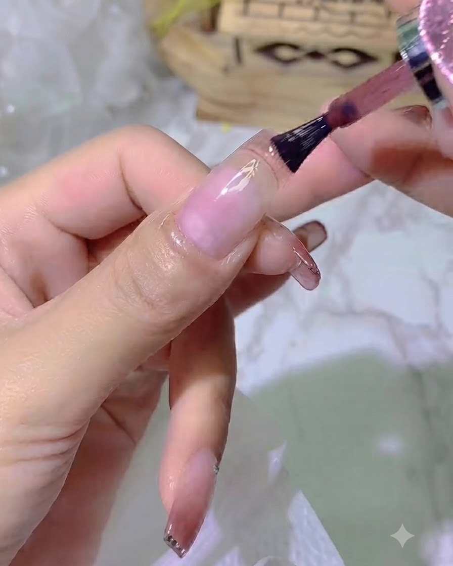 Eine Nahaufnahme eines Pinsels, der Jelly-Farbgel auf die Nagelplatte aufträgt, wobei ein kleiner Abstand zur Nagelhaut frei bleibt.