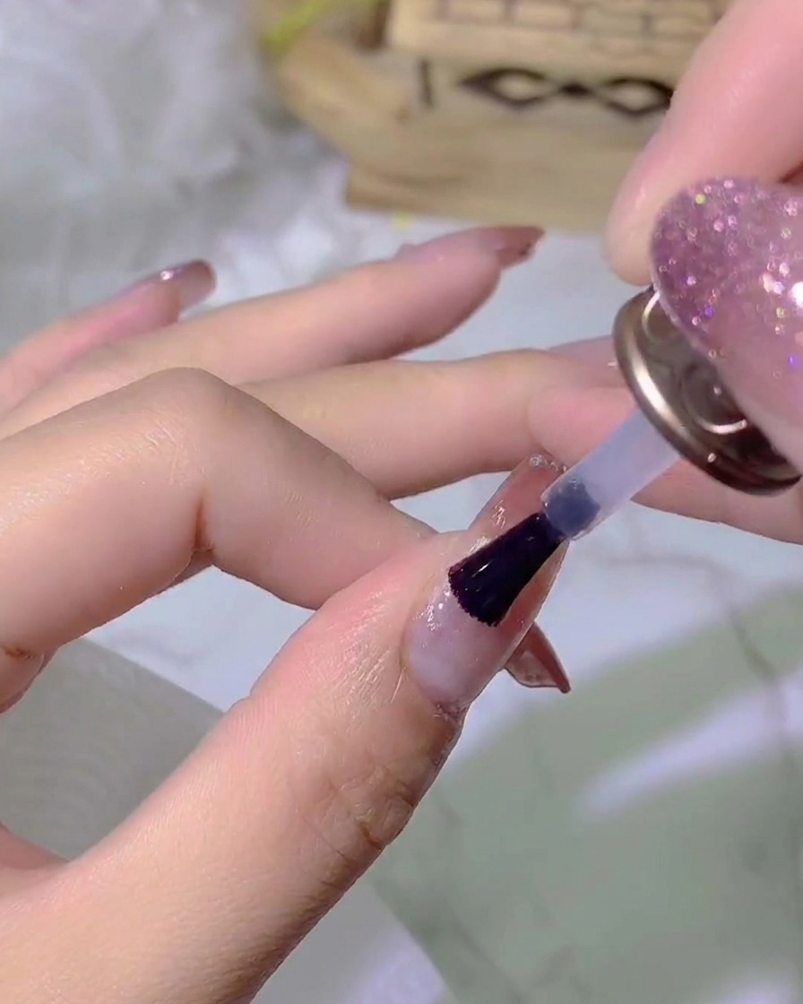 Eine Hand, die unter einer UV/LED-Nagellampe platziert ist und die Top-Coat-Schicht aushärtet.