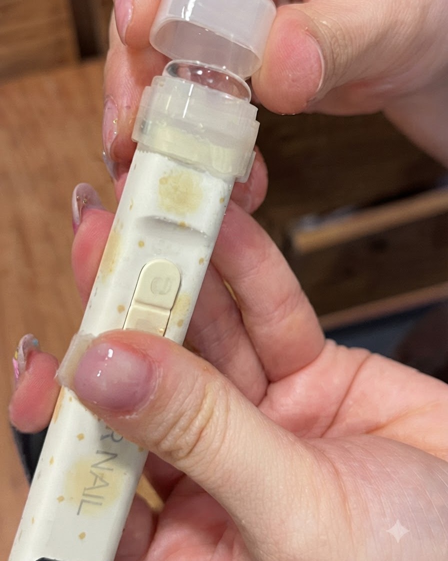 Eine tragbare UV/LED-Nagellampe mit einem klaren Silikon-Drückaufsatz wird über einen Finger gehalten.