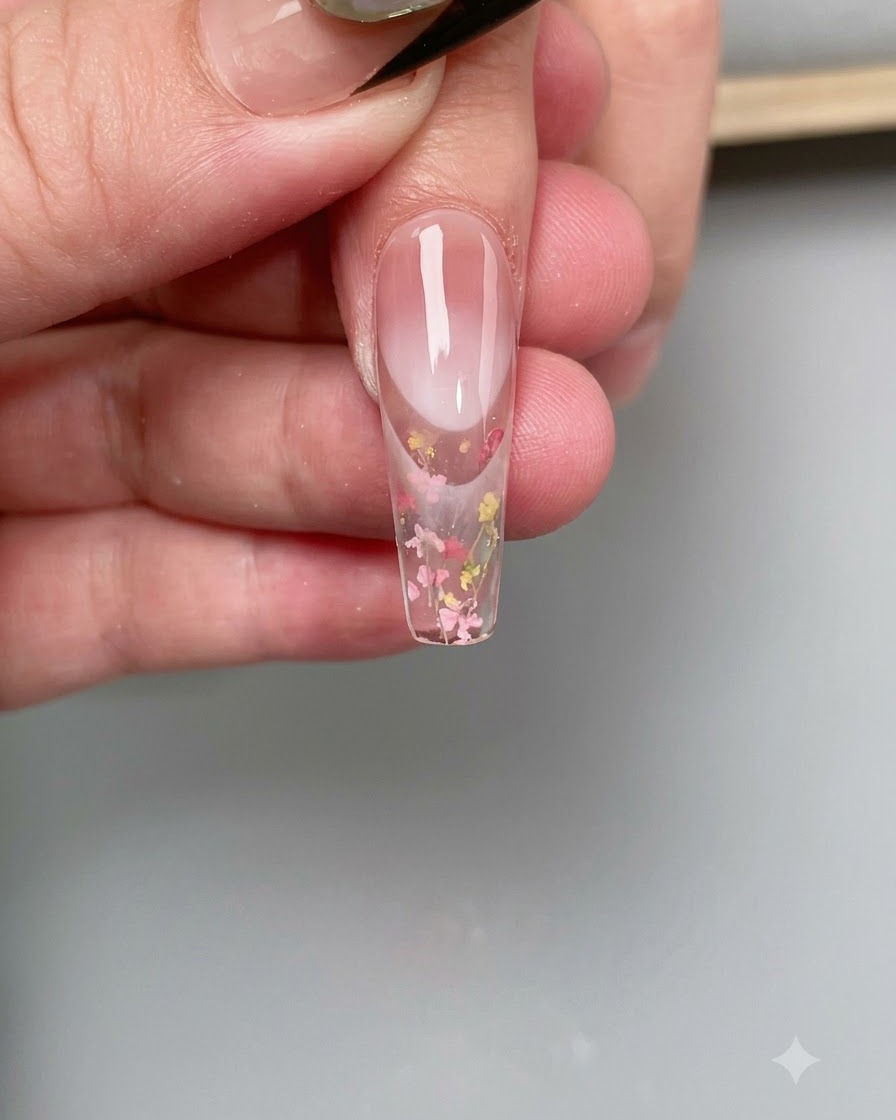 Ein feiner Pinsel trägt klaren Base-Coat auf die Oberfläche einer klaren Nagelspitze auf.