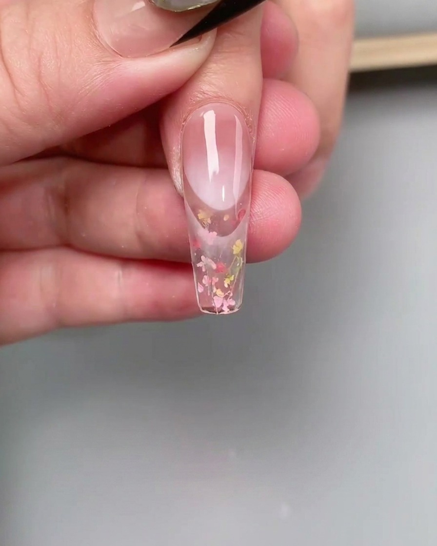 Ein feiner Liner-Pinsel verblendet rosa Gel-Lack am Nagelhautbereich eines Nagels, um einen Farbverlauf-Effekt zu erzeugen.