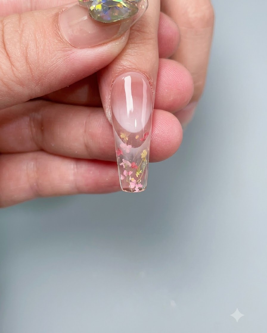 Ein Nagel mit eingebetteten Trockenblumen härtet in einer professionellen UV-/LED-Nagellampe aus.