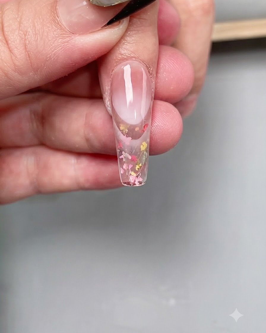 Ein feiner Nail-Art-Pinsel trägt einen klaren Diamant-Top-Coat präzise auf die Spitze eines langen sargförmigen Nagels auf.