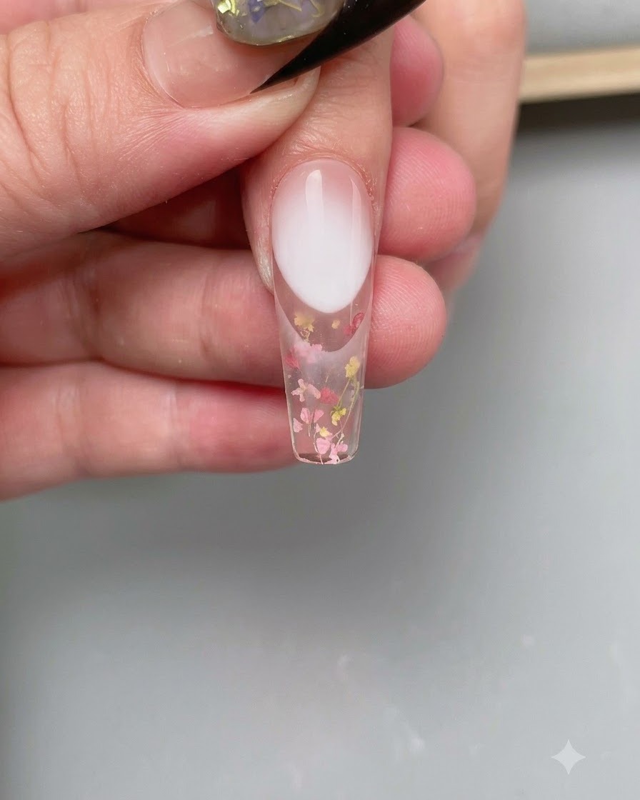 Eine Pinzette platziert eine geschwungene French-Nagelaufkleber-Schablone auf die Nagelspitze.