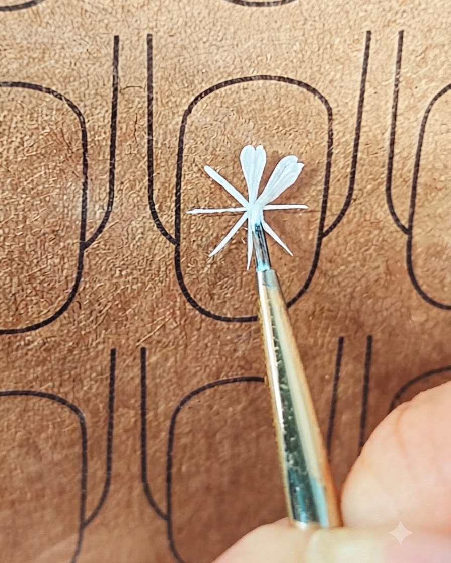 Ein feiner Nail-Art-Pinsel platziert weißes Gel, um ein zweites Blütenblatt auf einem Übungsboard zu formen.