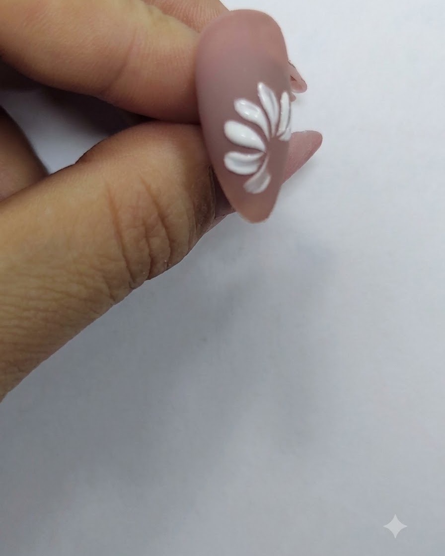 Ein vollendeter Ring aus weißen Blütenblättern, die eine vollständige Gänseblümchenblüte auf einem Nude-Nagelhintergrund bilden.