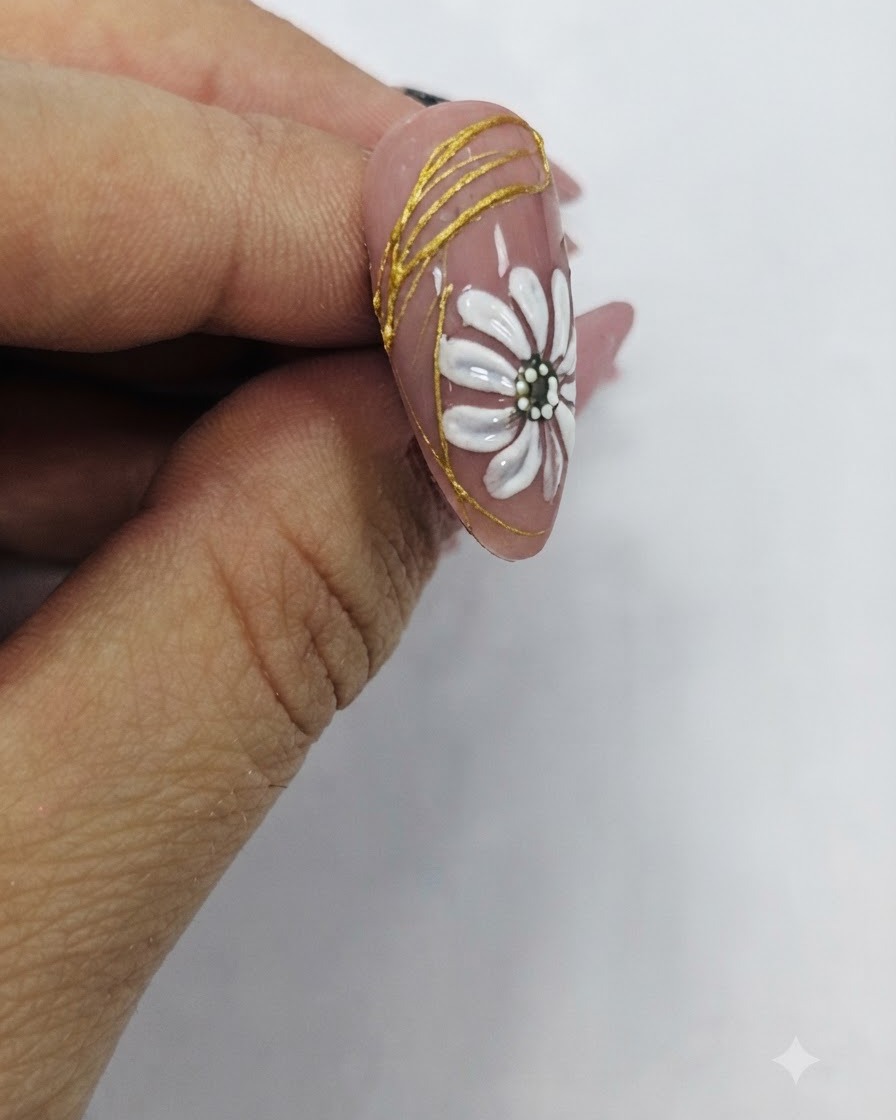 Ein Pinsel trägt einen glänzenden klaren Überlack über ein fertiges Nageldesign mit weißem Gänseblümchen und Goldakzenten auf.