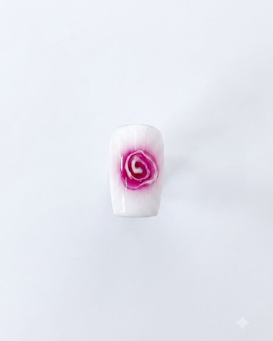 Ein fertiges Blooming-Rosen-Nagelkunst-Design mit einem roten Zentrum und weichen, sich ausbreitenden weißen Blütenblättern auf weißem Hintergrund.