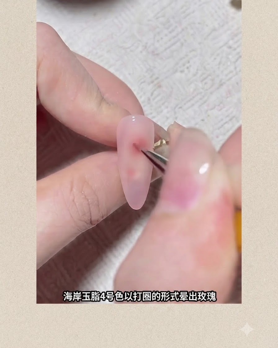 Ein feiner Nailart-Pinsel zeichnet einen rötlichen Pigmentpunkt auf einen mit Rosagel beschichteten Nagel, um eine blühende Blume zu formen.