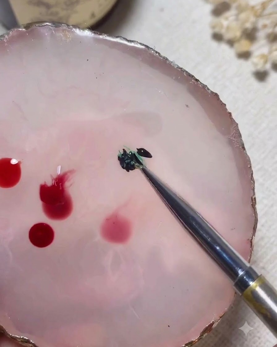 Ein Mischwerkzeug vermischt grüne und schwarze Gelfarben auf einer rosa Marmorpalette miteinander.