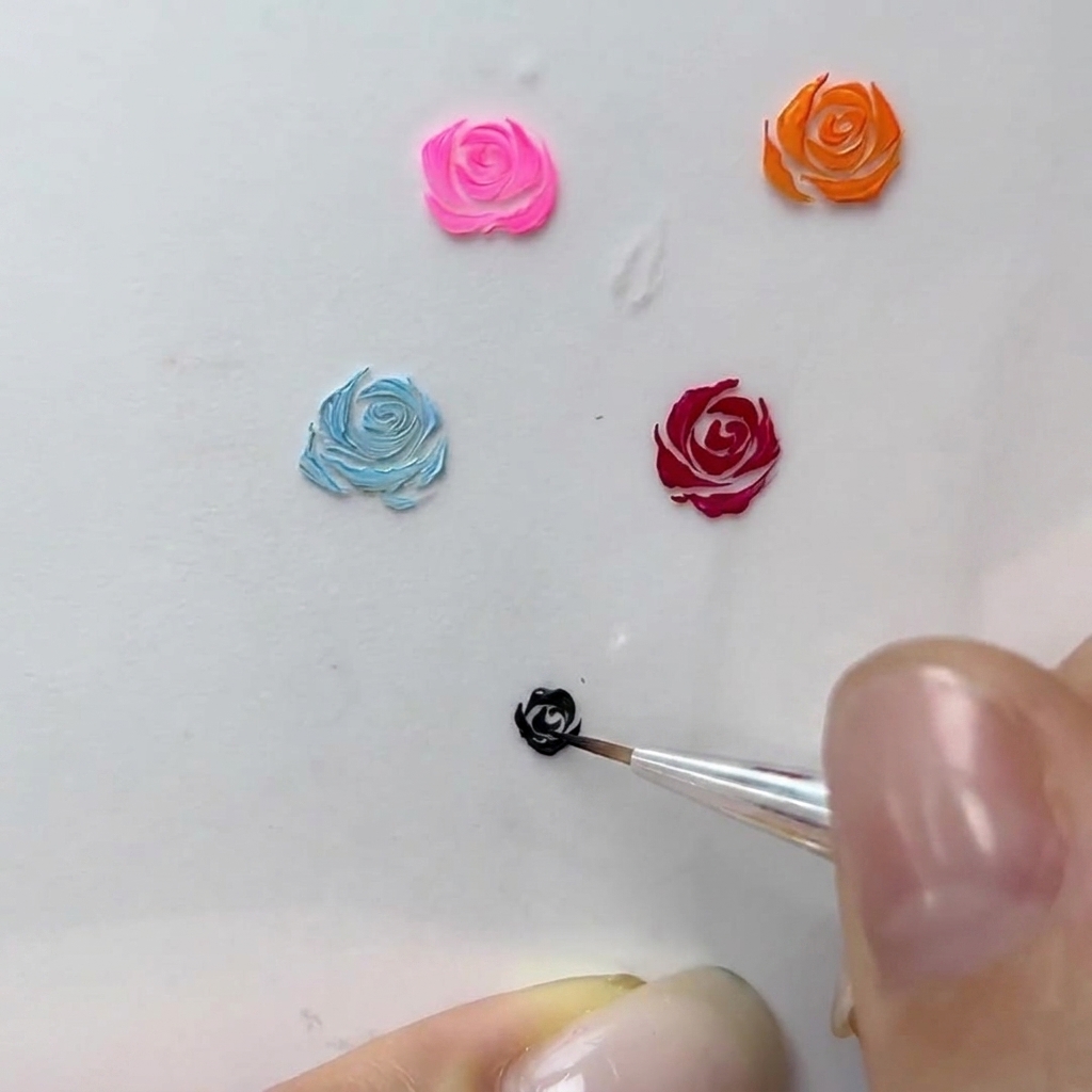 Eine Makroansicht eines Nail-Künstlers, der feine geschwungene Striche zum Rand einer schwarzen Gelrose hinzufügt.