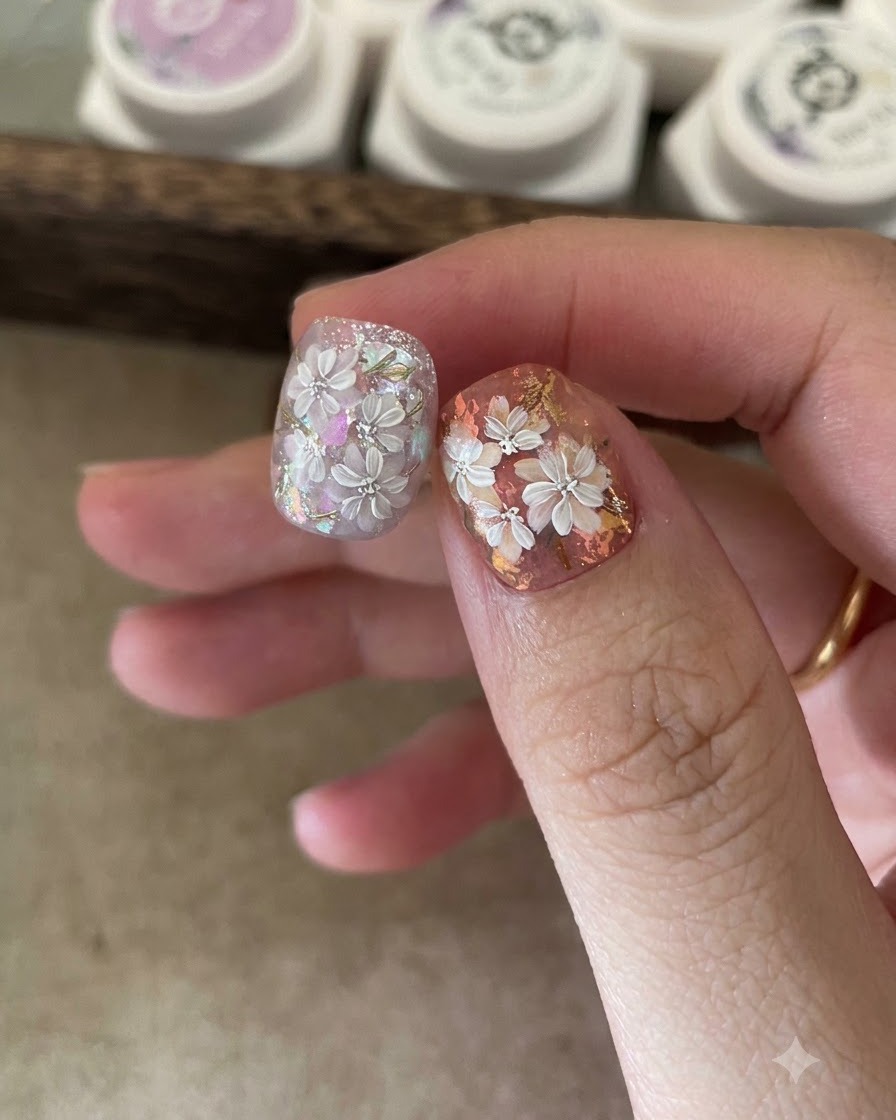 Ein Applikatorschwamm reibt Gold-Spiegelpuder auf die gemalten Blattdetails eines Nagels.
