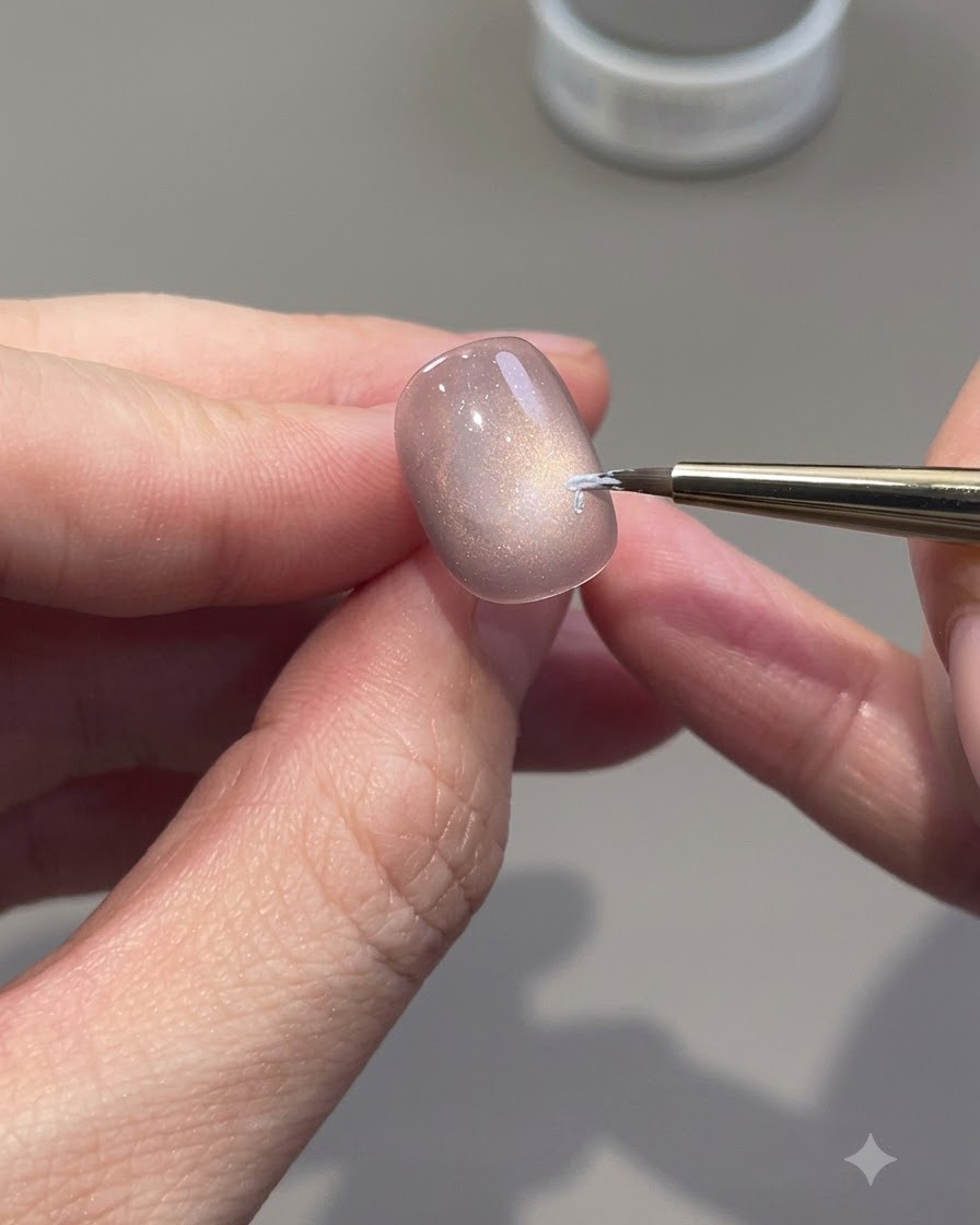 Ein feiner Liner-Pinsel zeichnet weiße Rosenumrisse auf einen Cat-Eye-Gel-Nagel.