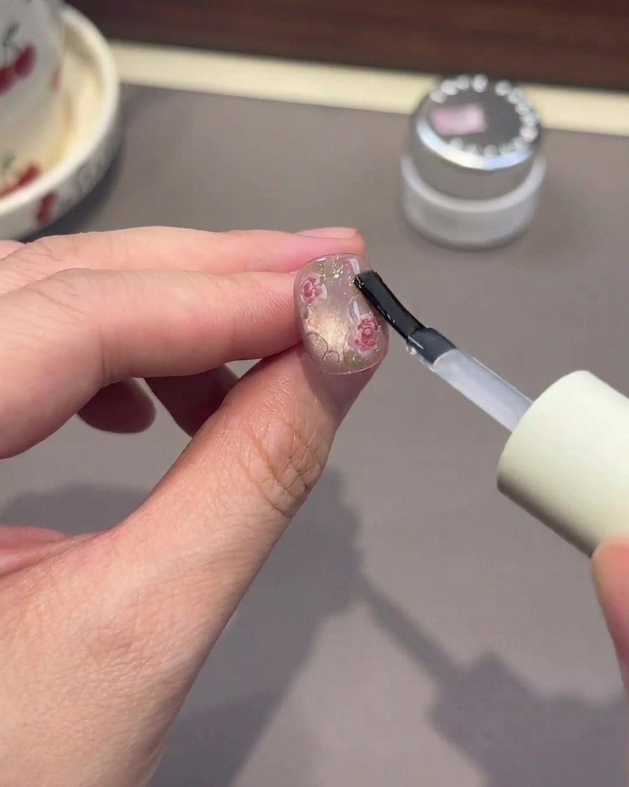 Ein Pinsel trägt dickes, klares Gel auf, um Wassertropfen-Effekte auf dem Nagel zu formen.