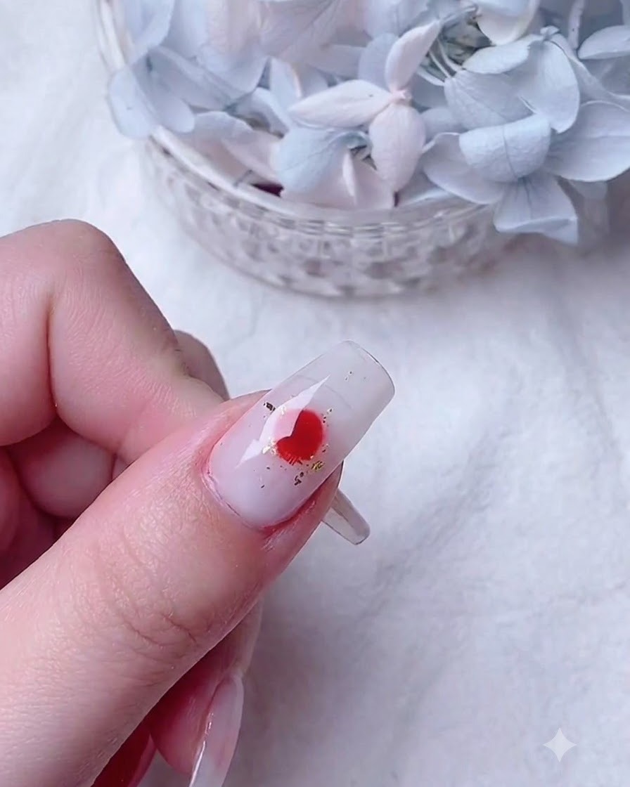 Ein feiner Detailpinsel tropft leuchtend rotes Gel auf die feuchte Blooming-Basis, um verlaufende Blütenblattformen zu erzeugen.