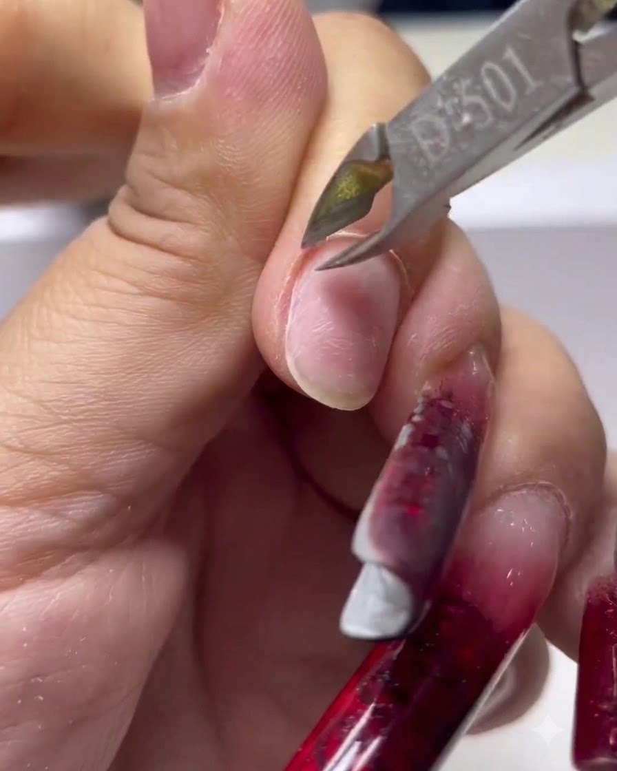 Eine Nahaufnahme von scharfen Nagelzangen aus Metall, die abgestorbene Haut von der Basis des Fingernagels abschneiden.