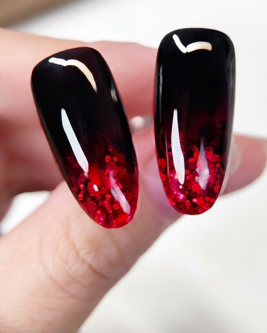 Eine Nahaufnahme eines Pinsels, der funkelnde rote Glitterflocken über den unteren Bereich einer dunkel lackierten Nagelverlängerung verteilt.