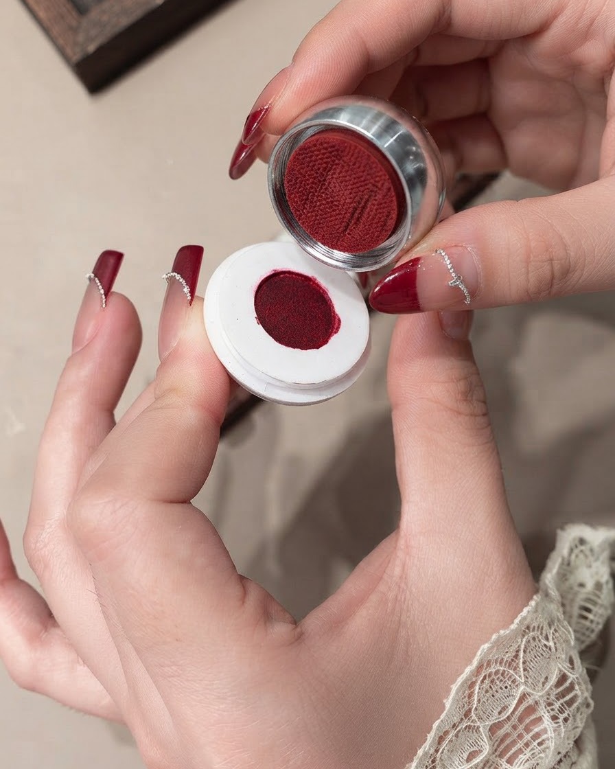 Nahaufnahme eines Pinsels, der rotes Samtgel auf einem Nagel glättet.