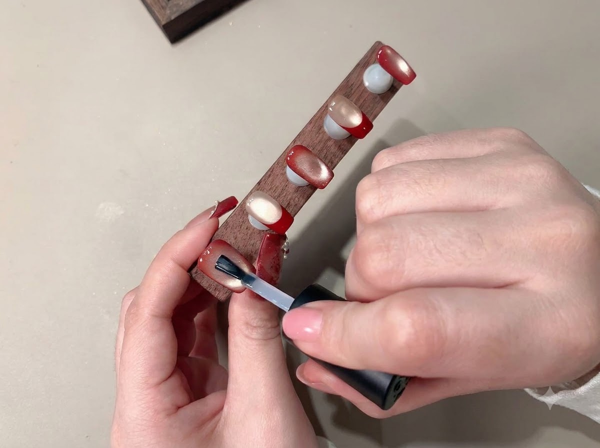 Ein Pinsel trägt einen klaren Topcoat auf, um das fertige Nail-Art zu versiegeln.