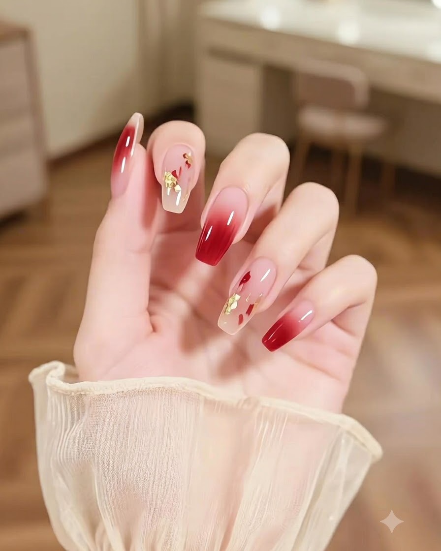 Eine Nahaufnahme einer Hand mit einem Akzentnagel mit abstrakten, mehrfarbigen Pinselstrichen und Goldfunkeln neben Burgunder-Ombré-Nägeln.