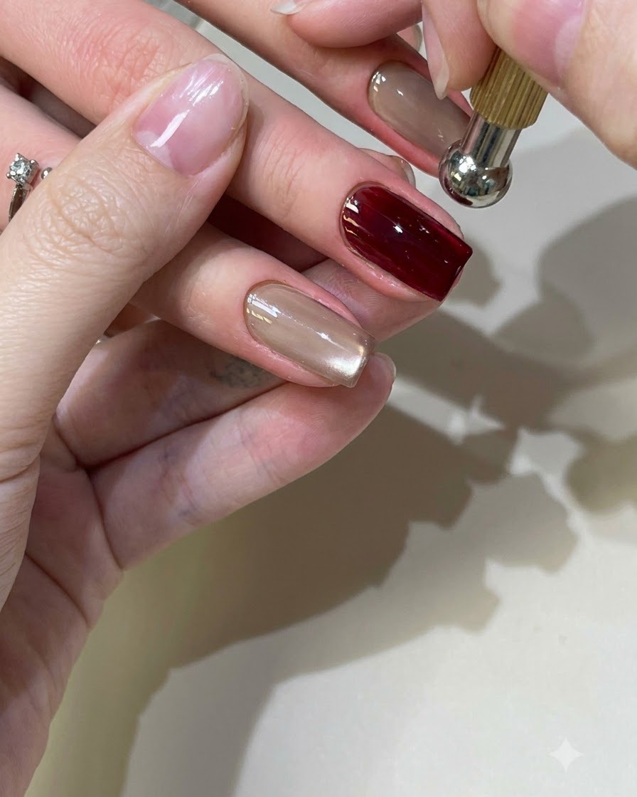 Ein kugelförmiges Magnetwerkzeug schwebt über einem roten Cat-Eye-Gel-Nagel, um die Lichtreflexion zu formen.